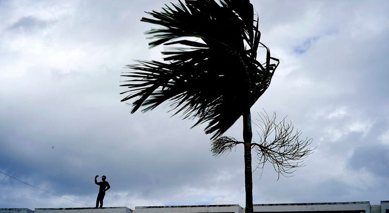 A man stands on a store's roof as he works to prepare it for the arrival of Hurricane Dorian in Freeport on Grand Bahama, Bahamas, A man stands on a store's roof as he works to prepare it for the arrival of Hurricane Dorian in Freeport on Grand Bahama, Bahamas,