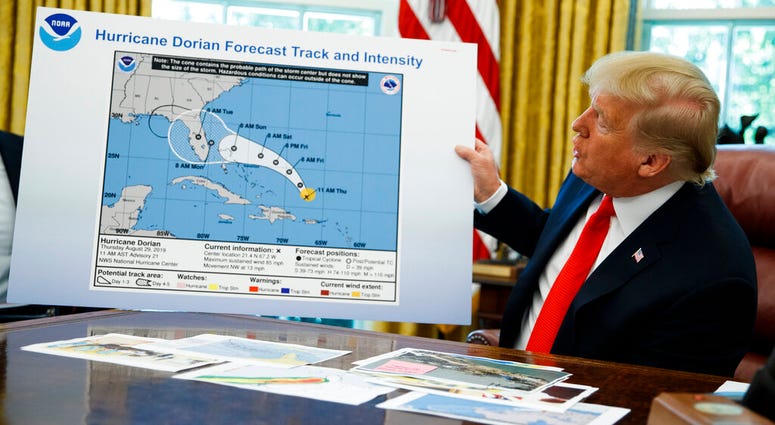President Donald Trump holds a chart as he talks with reporters after receiving a briefing on Hurricane Dorian in the Oval Office of the White House, Wednesday, Sept. 4, 2019, in Washington.