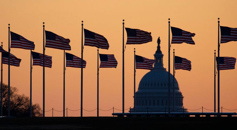 American flags blow in wind around the Washington Monument with the U.S. Capitol in the background at sunrise on Monday, Jan. 20, 2020, in Washington. The impeachment trial of President Donald Trump will resume in the U.S. Senate on Jan. 21.