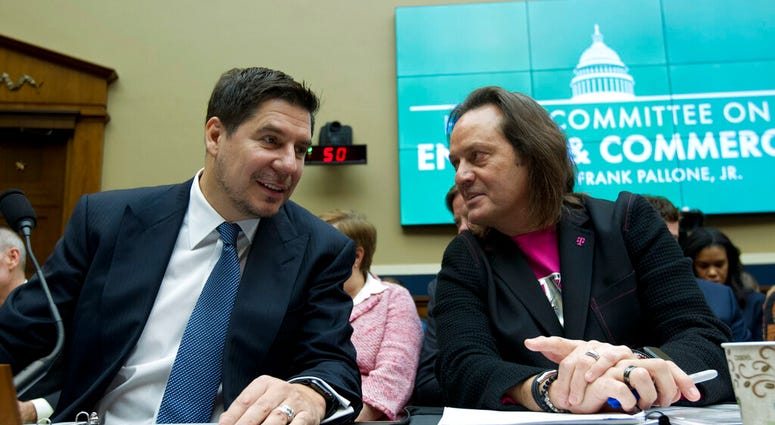 Sprint Corporation Executive Chairman Marcelo Claure, left, speaks with T-Mobile US CEO and President John Legere during the House Commerce subcommittee hearing on Capitol Hill in Washington. A federal judge has removed a major obstacle to T-Mobile's $26.