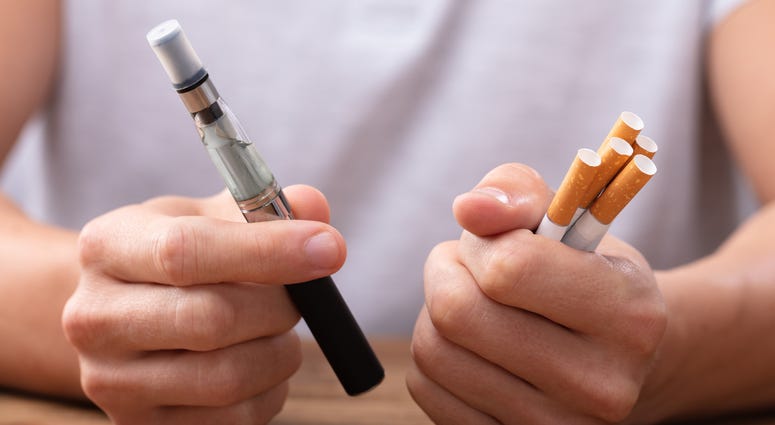 man holding a vaping stick and cigarettes