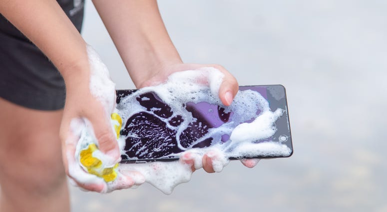 cell phone in hands is wet and covered in foam cell phone in hands is wet and covered in foam