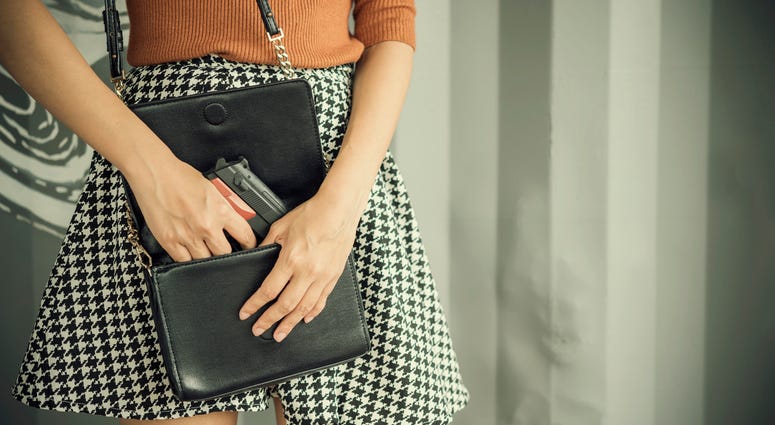 woman pulling a gun out of her purse