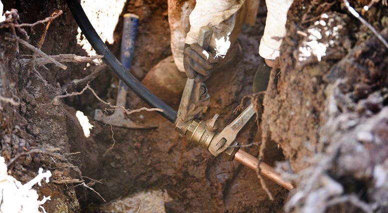 connects the new pipe with a test pipe as he works on lead pipe replacement