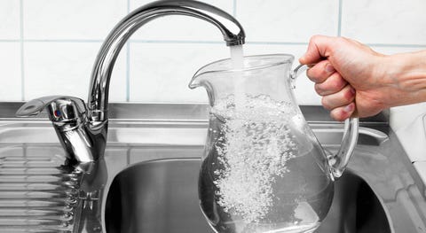 Pitcher being filled with drinking water from kitchen faucet. Pitcher being filled with drinking water from kitchen faucet.