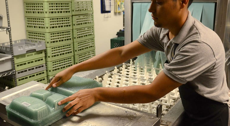 Antoni Fajaro, student from Los Angeles, washes re-usable go containers that students used to fill with food, then they are inserted into the OZZI machine which refunds the $5 deposit on the tray. Antoni Fajaro, student from Los Angeles, washes re-usable go containers that students used to fill with food, then they are inserted into the OZZI machine which refunds the $5 deposit on the tray.