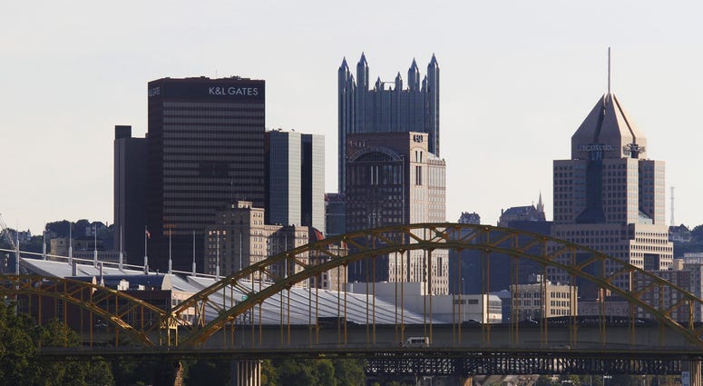 A landscape view of Downtown Pittsburgh with a team of rowers going down the Allegheny River Downtown Pittsburgh