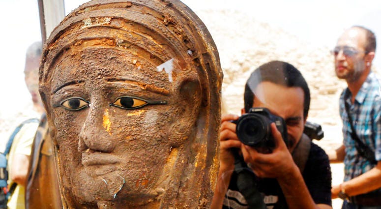 A photographer films a gilded silver mummy mask found on the face of the mummy of the second priest of Mut, DO NOT USE