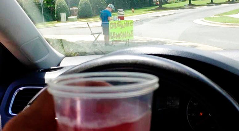 photo provided by James Castellano, of Monroe, N.C., shows a drink he bought from a boy, background, in Monroe. A teenager who held up the North Carolina lemonade stand for $17 was still at large Monday. DO NOT USE