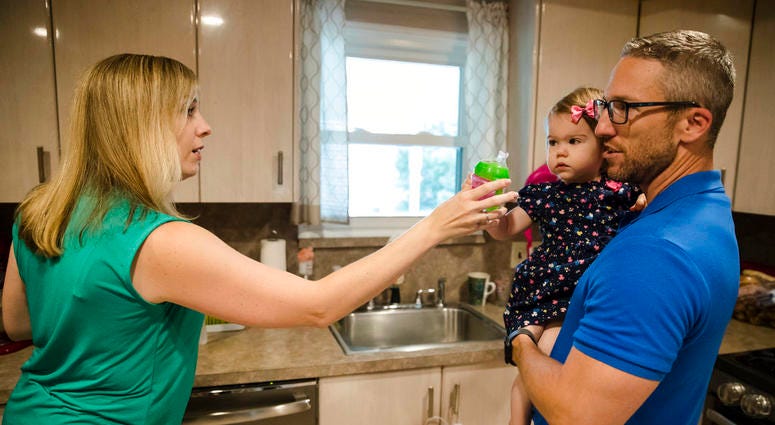 Lauren Woehr hands her 16-month-old daughter Caroline, held by her husband Dan McDowell, a cup filled with bottled water at their home in Horsham, Pa. DO NOT USE