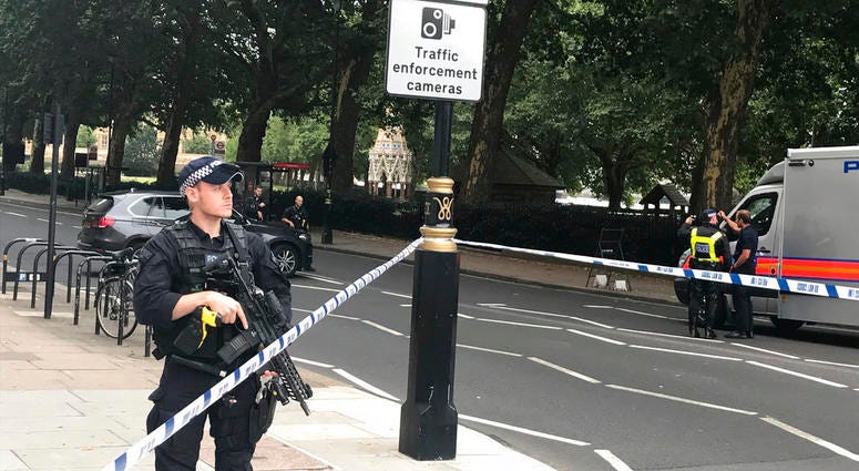 Police cordon off the area on Millbank, in central London, after a car crashed into security barriers outside the Houses of Parliament, in London, Tuesday, Aug. 14, 2018.