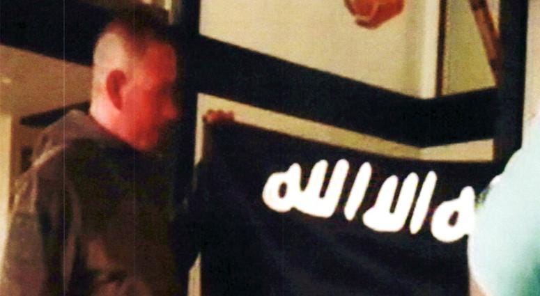 file image taken from FBI video and provided by the U.S. Attorney's Office in Hawaii on July 13, 2017, Army Sgt. 1st Class Ikaika Kang holds an Islamic State group flag after allegedly pledging allegiance to the terror group at a house in Honolulu. DO NOT USE