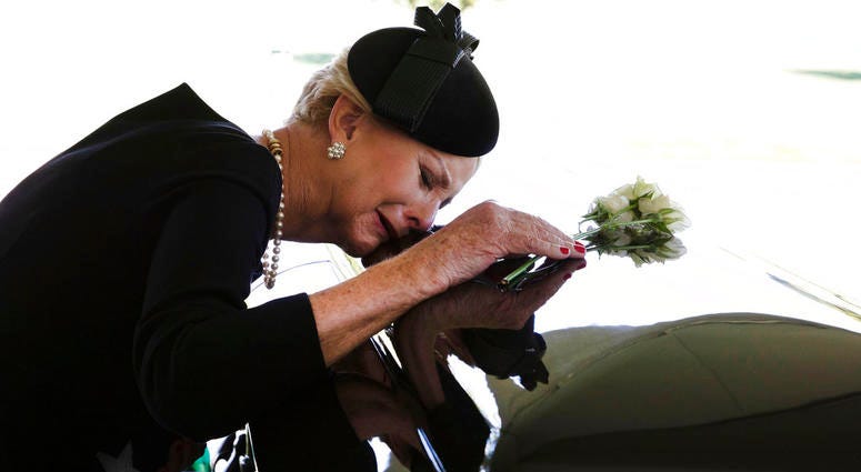 In this photo provided by the family of John McCain, Cindy McCain lays her head on the casket of Sen. John McCain, R-Ariz., during a burial service at the cemetery at the United States Naval Academy in Annapolis, Md., on Sunday, Sept. 2, 2018. DO NOT USE