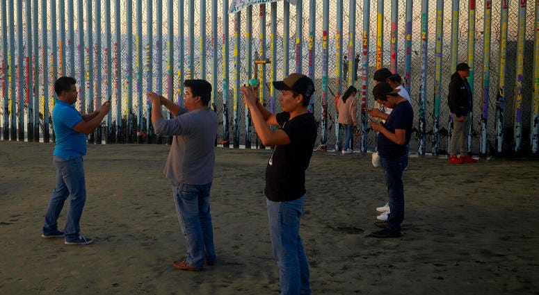 People record with their phones in front of the border wall AP DO NOT USE