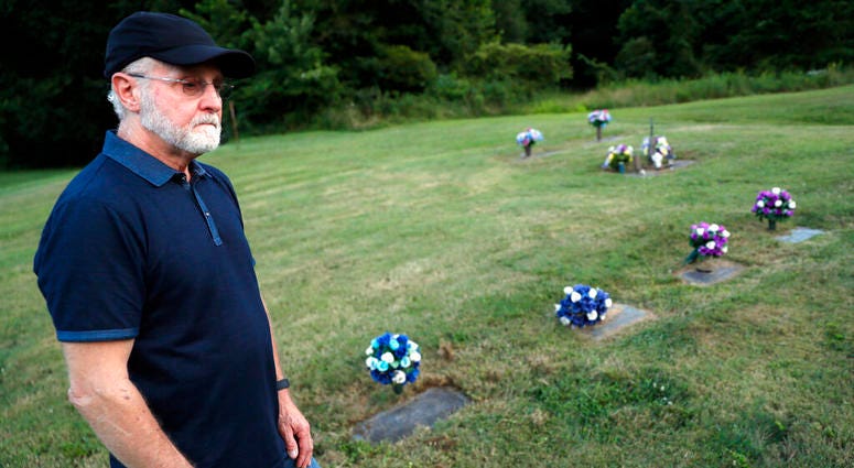 Eddie Davis stands beside the gravestone of his son Jeremy, furthest left, who died from the abuse of opioids, Wednesday, July 17, 2019, in Coalton, Ohio. AP DO NOT USE