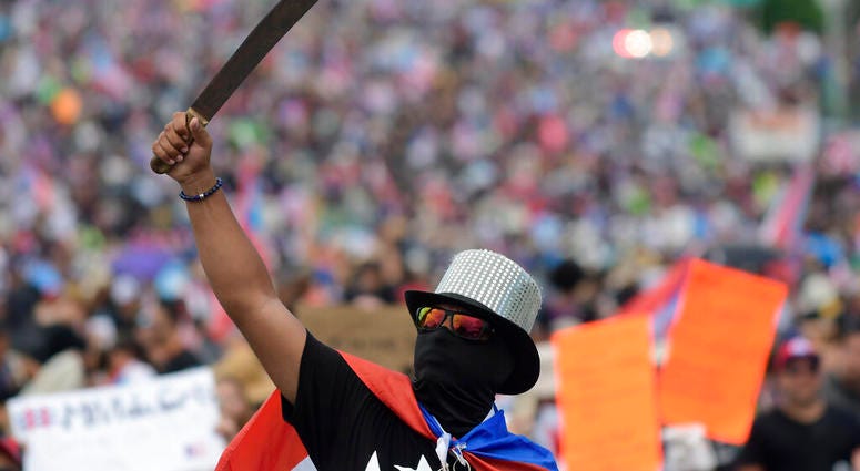 A demonstrator brandishes a machete during a march on Las Americas highway to demand the resignation of governor Ricardo Rossello, in San Juan, Puerto Rico, Monday, July 22, 2019. AP DO NOT USE