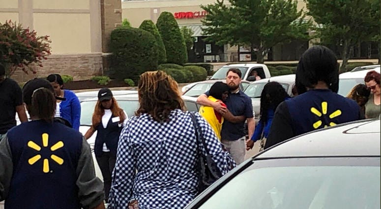In this image provided by WREG-TV, Walmart employees join in a prayer circle outside the store Tuesday, July 30, 2019, in Southaven, Miss. DeSoto County Sheriff Bill Rasco says one person is dead and a suspect was shot.