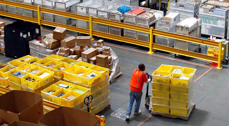 a worker pushes bins at an Amazon fulfillment center in Baltimore. a worker pushes bins at an Amazon fulfillment center in Baltimore.