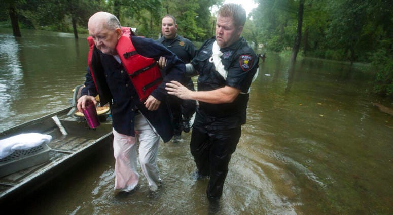 Fred Stewart, left, is helped to high ground by Splendora Police officer Mike Jones after he was rescued from his flooded neighborhood as rains from Tropical Depression Imelda inundated the area, Thursday, Sept. 19, 2019, in Splendora, Texas. AP DO NOT USE