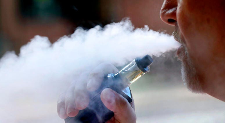 a man exhales while smoking an e-cigarette a man exhales while smoking an e-cigarette