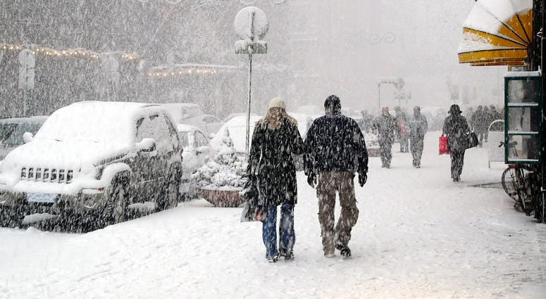 People walking down sidewalks in a snow storm in a city People walking down sidewalks in a snow storm in a city