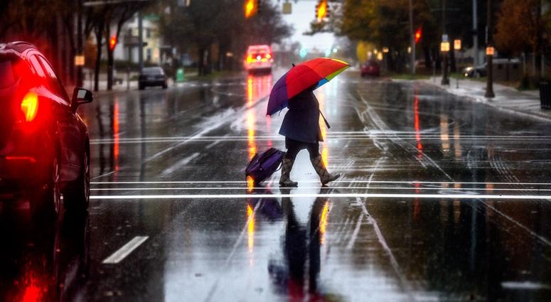 A pedestrian carries a colorful umbrella A pedestrian carries a colorful umbrella