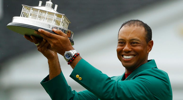Tiger Woods wears his green jacket holding the winning trophy after the final round for the Masters golf tournament Sunday, April 14, 2019, in Augusta, Ga. AP DO NOT USE