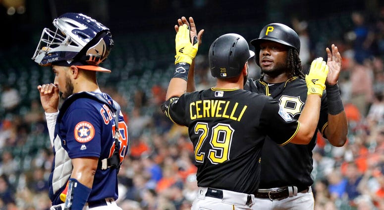 Pirates' Francisco Cervelli (29) celebrates with Josh Bell, right, after they scored on Cervelli's home run as Houston Astros catcher Robinson Chirinos, left, looks toward the field during the first inning of an exhibition baseball game Monday, DO NOT USE