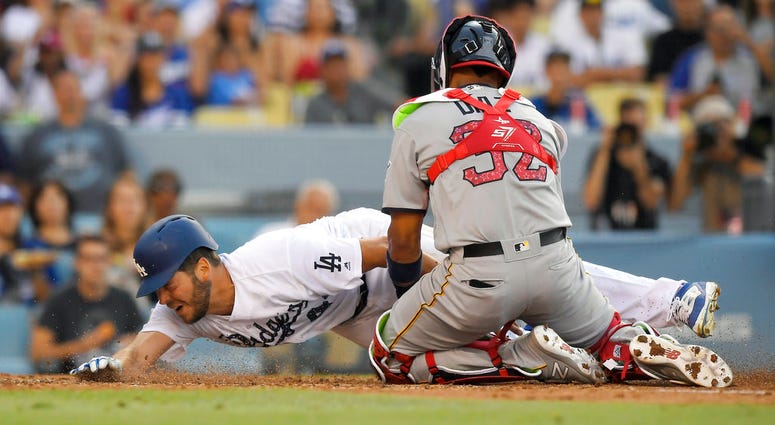 Los Angeles Dodgers' Rich Hill, left, is tagged out by Pittsburgh Pirates catcher Elias Diaz as he tried to score on a fly out by Max Muncy during the fourth inning of a baseball game DO NOT USE
