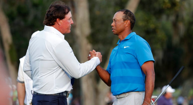 In this May 10, 2018, file photo, Phil Mickelson, left, and Tiger Woods shake hands after the first round of the Players Championship golf tournament DO NOT USE