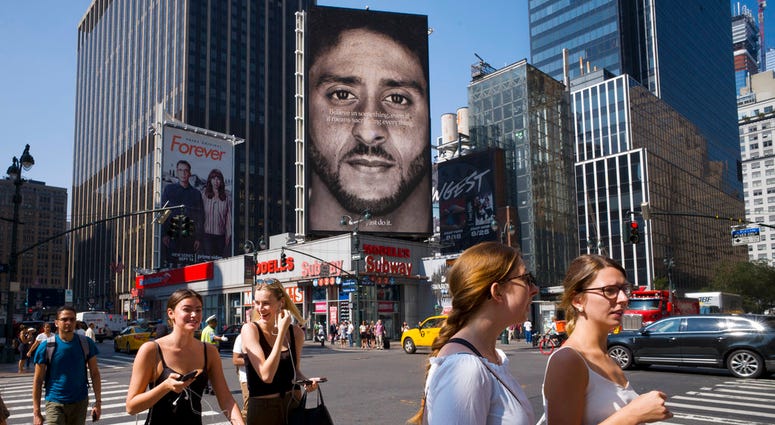 In this Sept. 6, 2018, file photo, people in New York walk past a Nike advertisement featuring former San Francisco 49ers quarterback Colin Kaepernick, DO NOT USE