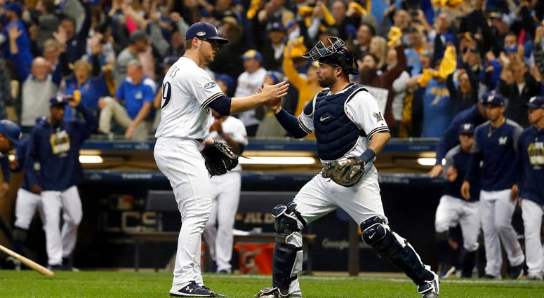 Milwaukee Brewers relief pitcher Corbin Burnes (39) and catcher Manny Pina (9) celebrate after Game 6 of the National League Championship Series baseball game against the Los Angeles Dodgers Friday, Oct. 19, 2018, in Milwaukee. DO NOT USE