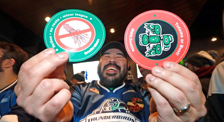 Otto Rogers playfully holds up stickers against the proposed name Kraken and in support of Totems following the announcement of a new NHL hockey team in Seattle, at a celebratory party Tuesday, Dec. 4, 2018, in Seattle DO NOT USE