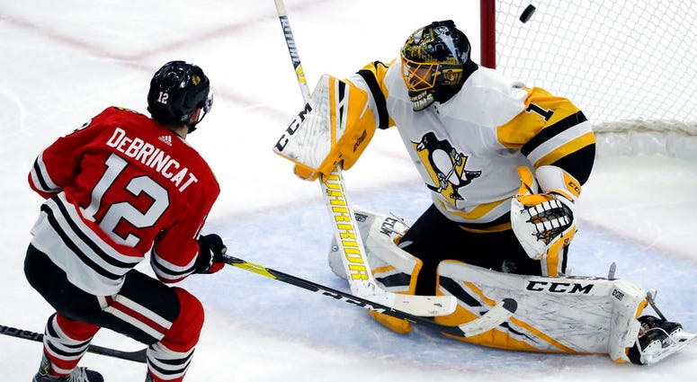 Chicago Blackhawks left wing Alex DeBrincat, left, scores against Pittsburgh Penguins goalie Casey DeSmith Chicago Blackhawks left wing Alex DeBrincat, left, scores against Pittsburgh Penguins goalie Casey DeSmith