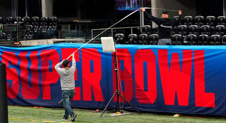 Workers use a tape measure as they hang a sign inside Mercedes-Benz Stadium for the NFL Super Bowl 53 football game AP DO NOT USE