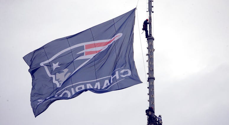 Workers secure a New England Patriots banner on a pole before the team parades through downtown Boston, Tuesday, Feb. 5, 2019, to celebrate their win over the Los Angeles Rams in Sunday's NFL Super Bowl 53 football game in Atlanta DO NOT USE
