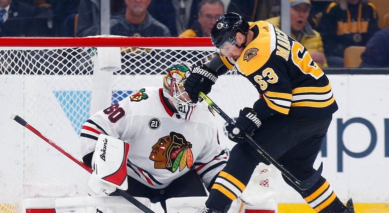 Boston Bruins' Brad Marchand (63) tries to get a shot on Chicago Blackhawks' Collin Delia (60) during the first period of an NHL hockey game in Boston, Tuesday, Feb. 12, 2019. AP DO NOT USE