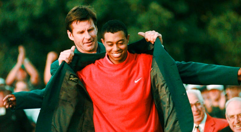 In this April 13, 1997, file photo, Masters champion Tiger Woods receives his Green Jacket from last year's winner Nick Faldo, rear, at the Augusta National Golf Club in Augusta, Ga. AP DO NOT USE