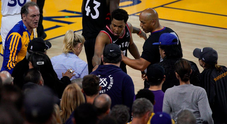 Toronto Raptors guard Kyle Lowry, middle, gestures next to referee Marc Davis (8) near the front row of fans during the second half of Game 3 of basketball's NBA Finals between the Golden State Warriors and the Raptors in Oakland, Calif. AP DO NOT USE
