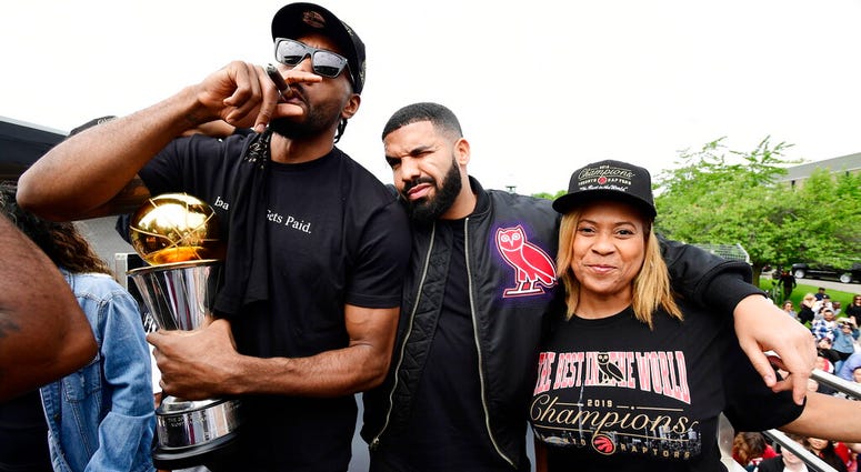 oronto Raptors forward Kawhi Leonard, left to right, smokes a cigar holding his playoffs MVP trophy as he celebrates with performing artist Drake and his mother Kim Robertson during the 2019 Toronto Raptors NBA basketball championship parade in Toronto, M AP DO NOT USE