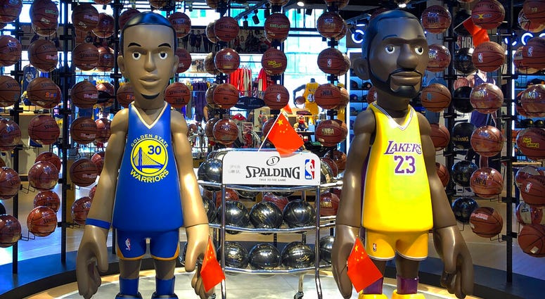 Statues of NBA players Stephen Curry of the Golden State Warriors, left, and Lebron James of the Los Angeles Lakers hold Chinese flags in the entrance of an NBA merchandise store in Beijing, Tuesday, Oct. 8, 2019. AP DO NOT USE