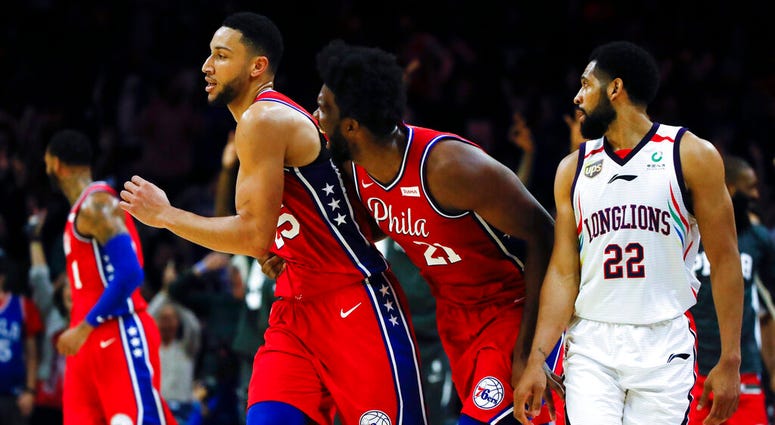 Philadelphia 76ers' Joel Embiid, center right, celebrates with Ben Simmons, center left, after he shot a 3-pointer to end the second quarter as Guangzhou Loong-Lions' CJ Harris, right, looks on during the first half of an NBA exhibition basketball game Tu AP DO NOT USE