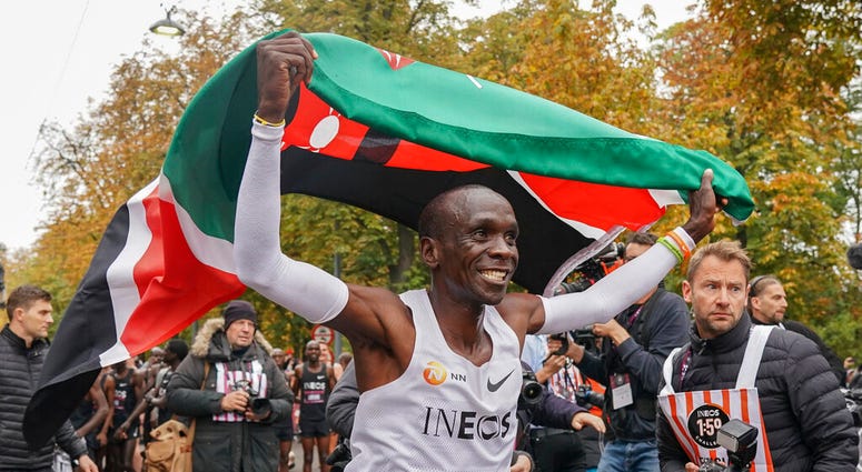 Eliud Kipchoge celebrates with the Kenyan flag after breaking the historic two hour barrier for a marathon in Vienna, Saturday, Oct. 12, 2019. AP DO NOT USE
