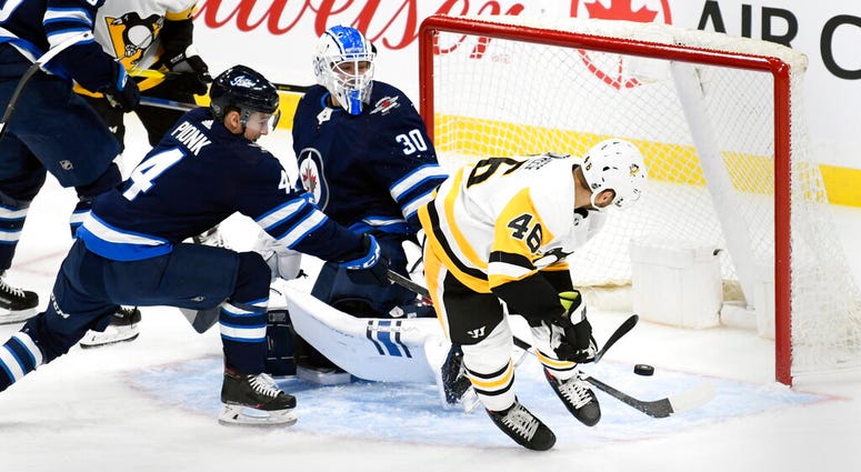 Pittsburgh Penguins' Zach Aston-Reese scores against Winnipeg Jets goaltender Laurent Brossoit Pittsburgh Penguins' Zach Aston-Reese scores against Winnipeg Jets goaltender Laurent Brossoit