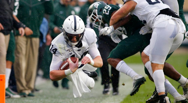 Penn State quarterback Sean Clifford, left, dives for a first down against Michigan State's Shakur Brown (29) during the first quarter of an NCAA college football game, Saturday, Oct. 26, 2019, in East Lansing, Mich.