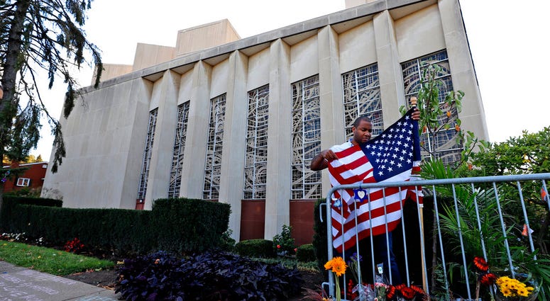 A man places an American flag outside the Tree of Life synagogue in Pittsburgh on Sunday, Oct. 27, 2019, the first anniversary of the shooting at the synagogue that killed 11 worshippers. AP DO NOT USE