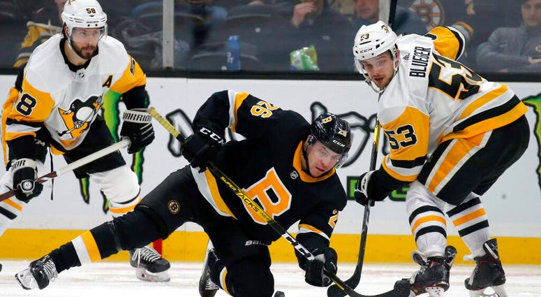 Boston Bruins center Par Lindholm (26) and Pittsburgh Penguins center Teddy Blueger (53) look to make a play for the puck during the third period of an NHL hockey game, Thursday, Jan. 16, 2020, in Boston.