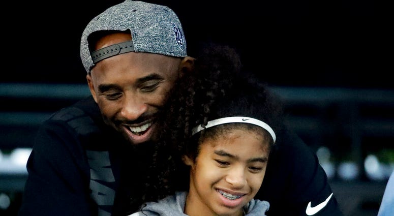 Kobe Bryant and his daughter Gianna watch during the U.S. national championships swimming meet in Irvine, Calif. Federal investigators say wreckage from the helicopter that crashed last month and killed Bryant, his daughter and seven others did not show a