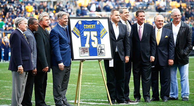 Former Pittsburgh Panthers player Jimbo Covert is surrounded by his former teammates after having his number retired at halftime between the Pittsburgh Panthers