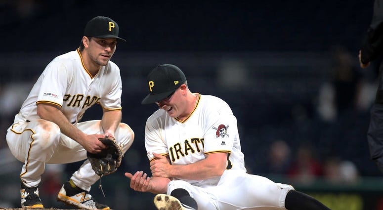 pitcher Nick Burdi (57) grabs his bicep after suffering an injury while pitching as second baseman Adam Frazier (26) looks on